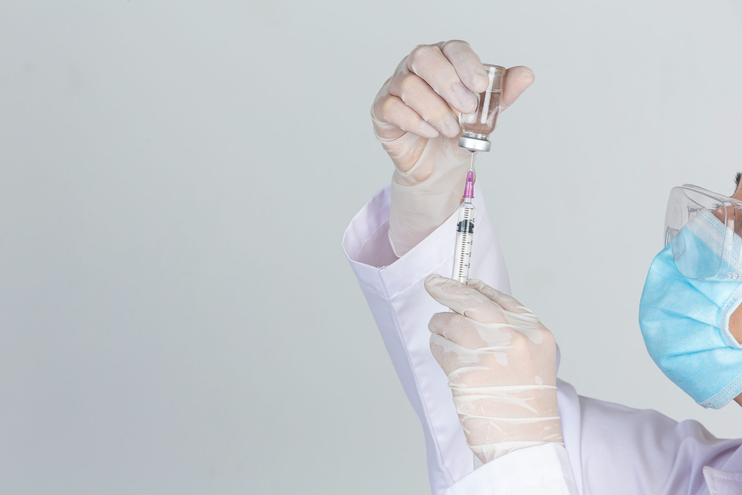 young doctor is holding hypodermic syringe with vaccine vial rubber gloves on gray wall scaled - Argentina recibirá casi 4 millones de dosis de AstraZeneca contra el Covid-19